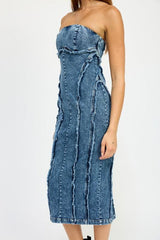Close-up of the side of a blue strapless denim midi dress with paneled construction and raw edge detailing.