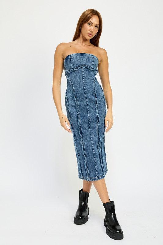 Woman wearing a blue strapless denim midi dress with paneled construction and raw edge detailing, standing with legs slightly apart.