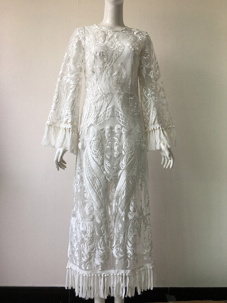 white lace dress on a mannequin, featuring long bell sleeves with fringe, a round neckline, and a midi length with a slit and fringe hem
