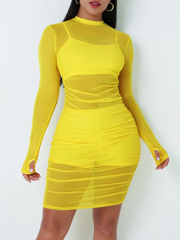 Woman wearing a long-sleeved yellow mesh ruched bodycon dress with a mock neckline.