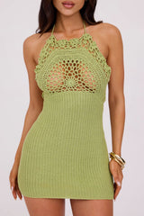 Woman wearing a green crochet halter mini dress against a white background.