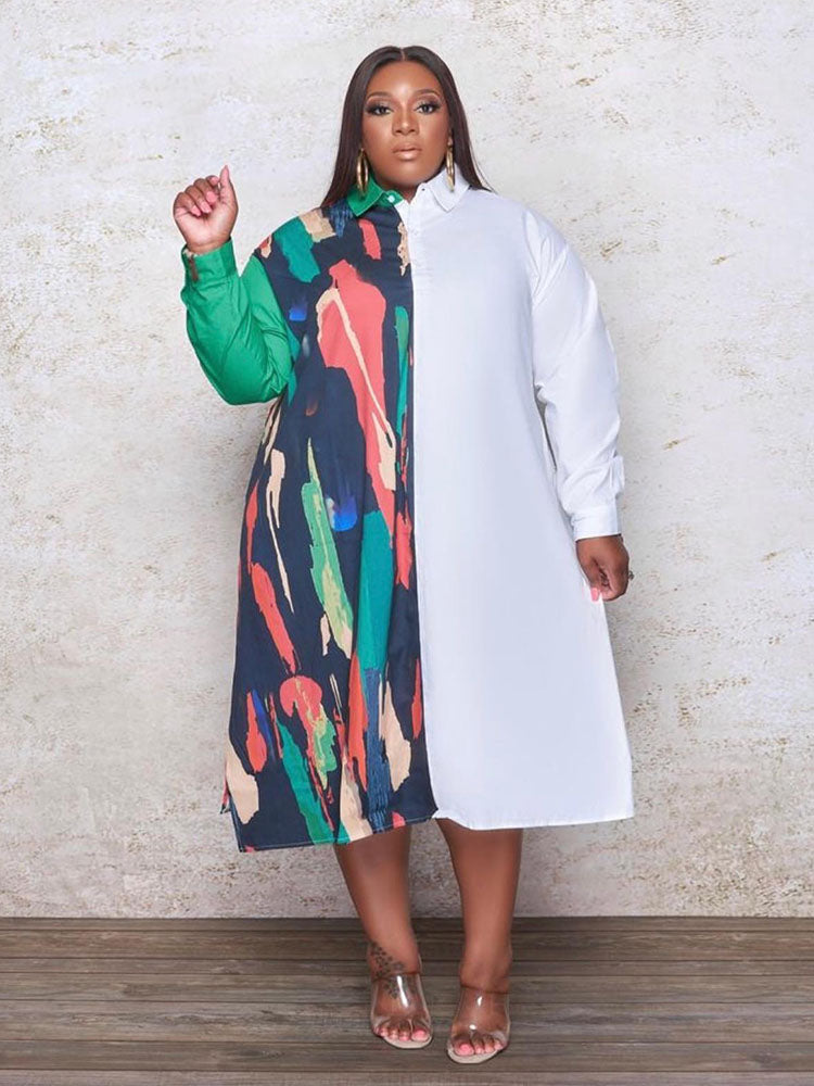 Plus-size woman wearing a long-sleeved, asymmetrical color block shirt dress with a white side and a printed side, standing against a textured wall.