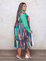 Side view of a plus-size woman wearing a long-sleeved, asymmetrical color block shirt dress with a white side and a printed side.