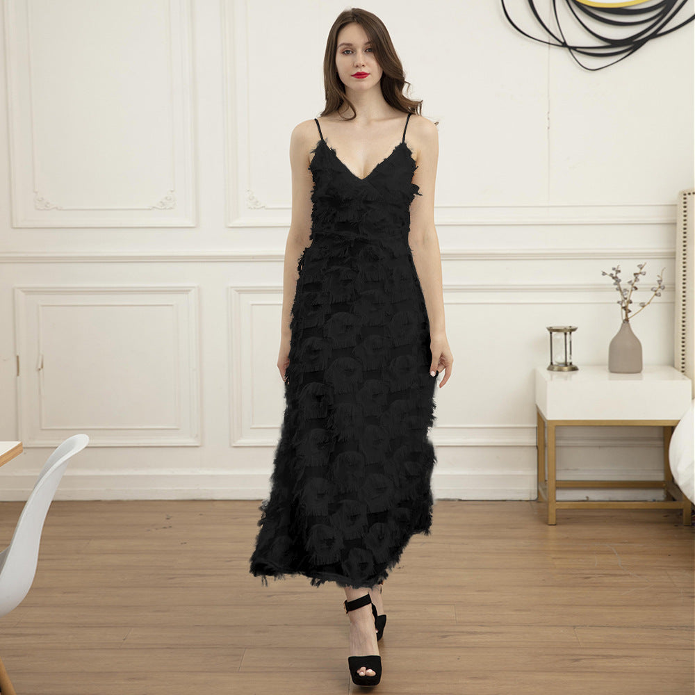 Woman wearing a black feather-trimmed midi dress with spaghetti straps and a v-neck, standing indoors.