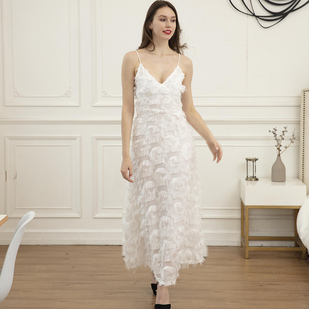 Woman wearing a white feather-trimmed midi dress with spaghetti straps and a v-neck, standing indoors.