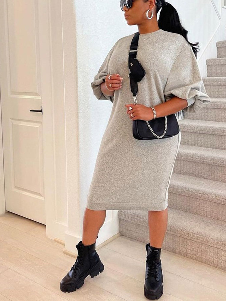 Woman in a grey knit midi dress with puff sleeves and black combat boots, standing on stairs.