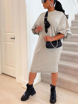 Woman in a grey knit midi dress with puff sleeves and black combat boots, standing on stairs.