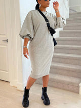 Woman wearing a grey knit midi dress with puff sleeves and black combat boots, with a black crossbody bag.