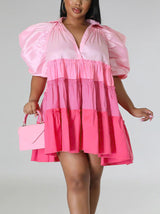Woman wearing a pink tiered mini dress with puff sleeves and a v-neck