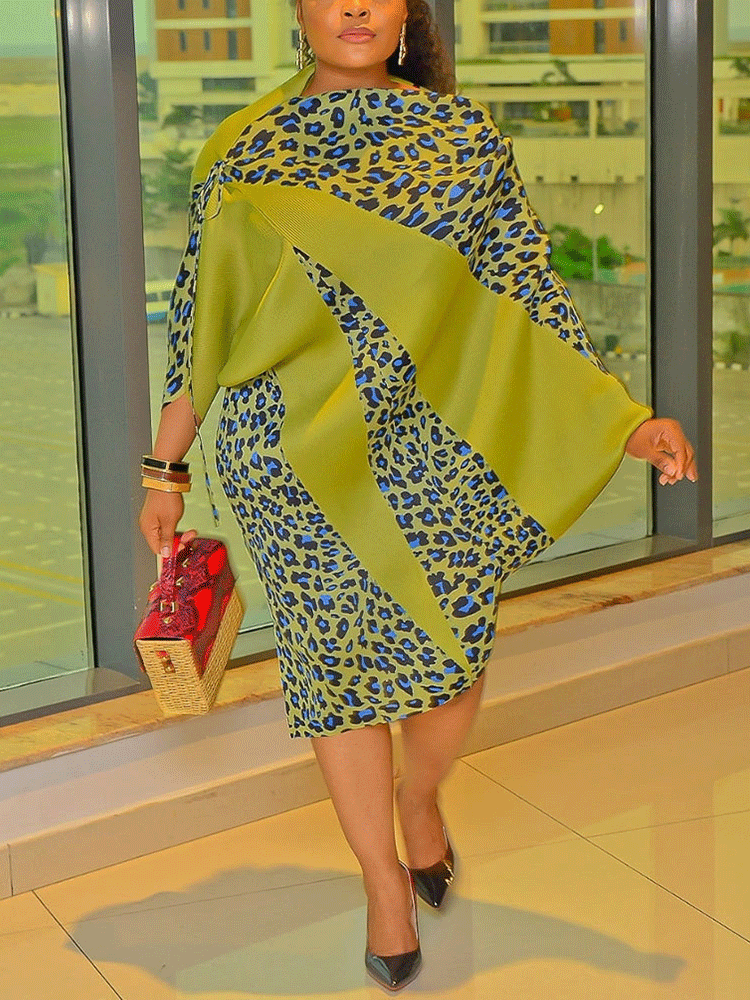 Woman in a green and leopard print dress with a draped overlay and a basket handbag.