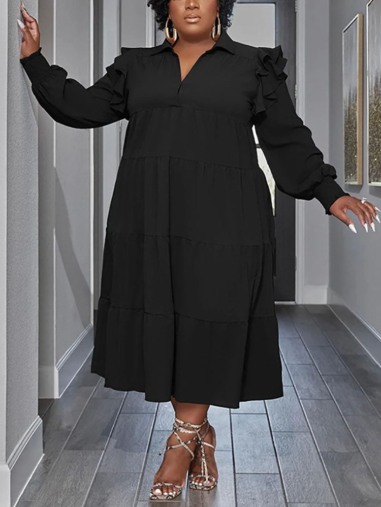 Plus-size model wearing a black tiered midi dress with voluminous sleeves and ruffled shoulders.