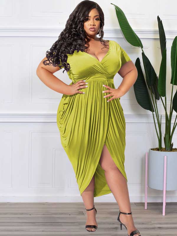 Plus-size model in a lime green ruched V-neck short-sleeve dress with a tulip hem and side slit, showcasing a silver cuff bracelet.