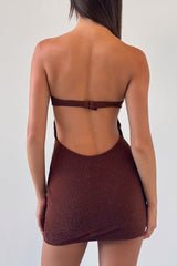 Woman wearing a brown strapless mini dress with a cut-out and ring detail, back view