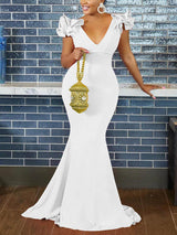 Woman wearing a white mermaid-style formal gown with ruffled cap sleeves and a deep V-neckline.