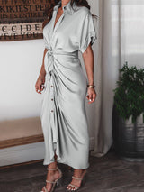 Close-up of the front of a light gray satin maxi dress showing the button-down detail and tie waist.