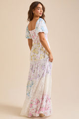 Back view of a woman wearing a white floral print maxi dress with puff sleeves and a square neckline.