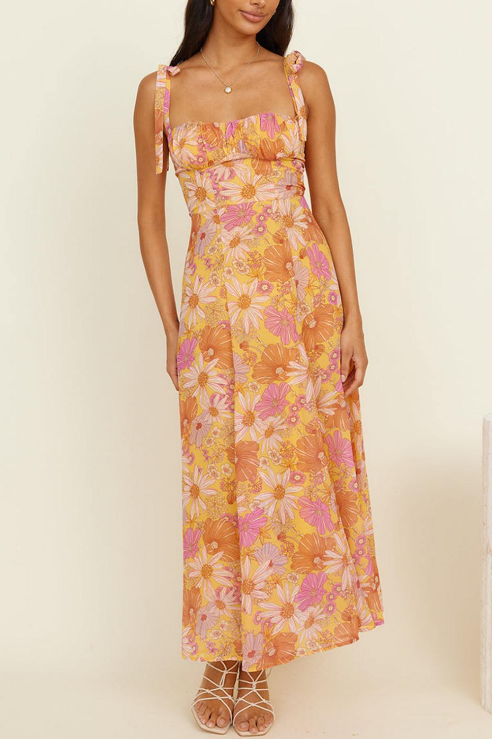 woman wearing a yellow midi dress with a pink and orange floral print, featuring tie shoulder straps and a square neckline