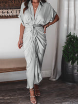 Side view of a woman in a light gray satin maxi dress with ruched detailing and a tie waist.