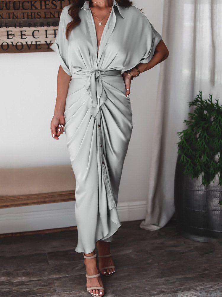 Side view of a woman in a light gray satin maxi dress with ruched detailing and a tie waist.