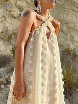 Detail shot of the halter neckline and floral embellishments on the cream-colored maxi dress.