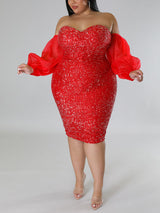 A plus-size model stands in a red sequined off-the-shoulder dress with flowing puff sleeves.