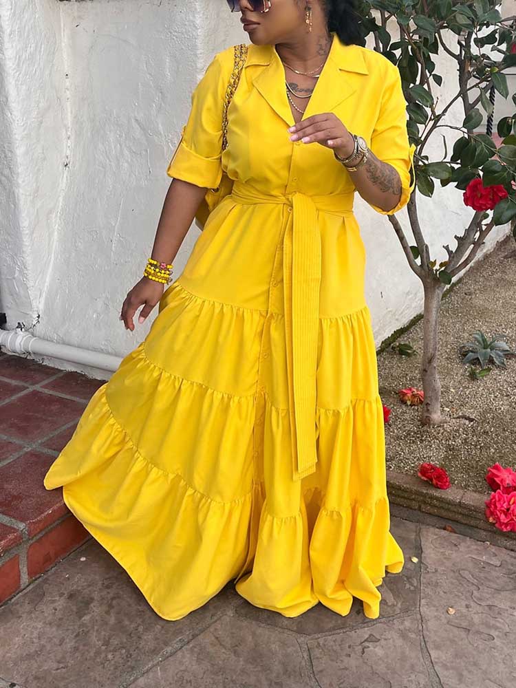 Woman wearing a yellow tiered maxi dress with a collared neckline and a belted waist.
