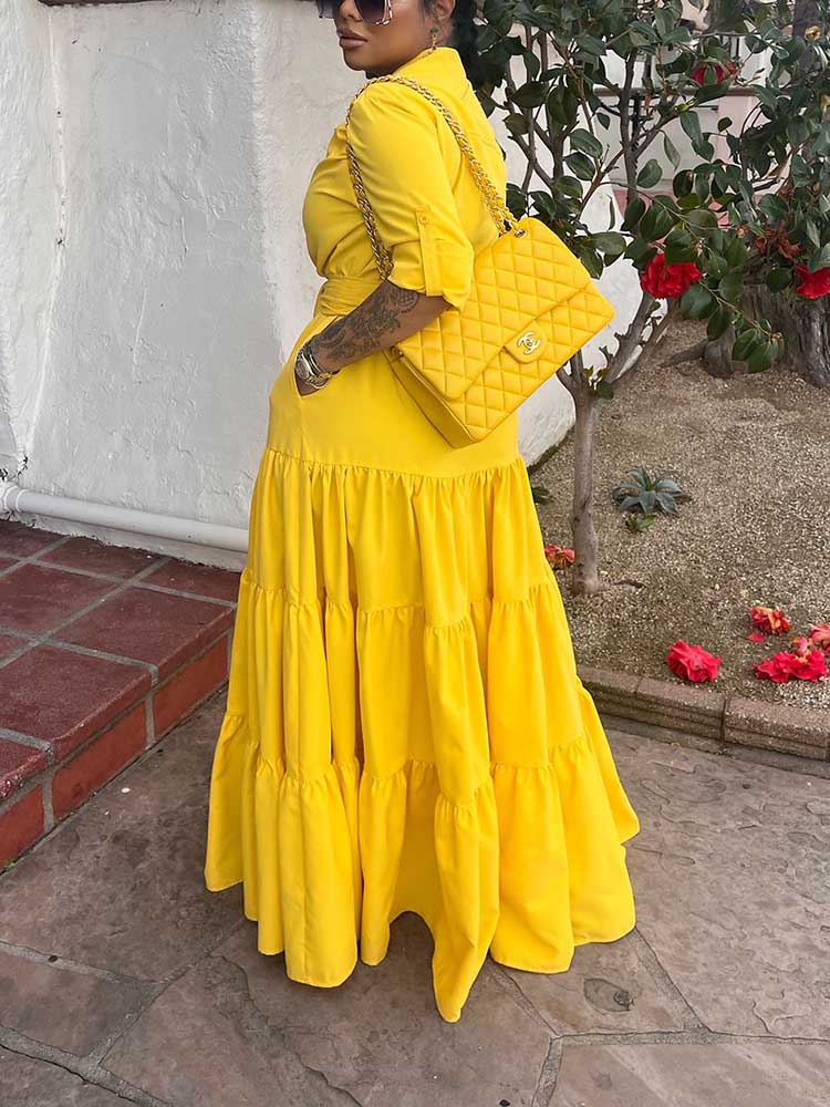 Side view of a woman wearing a yellow tiered maxi dress.
