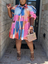 Full shot of a woman in a vibrant tie-dye tiered dress, holding a small handbag