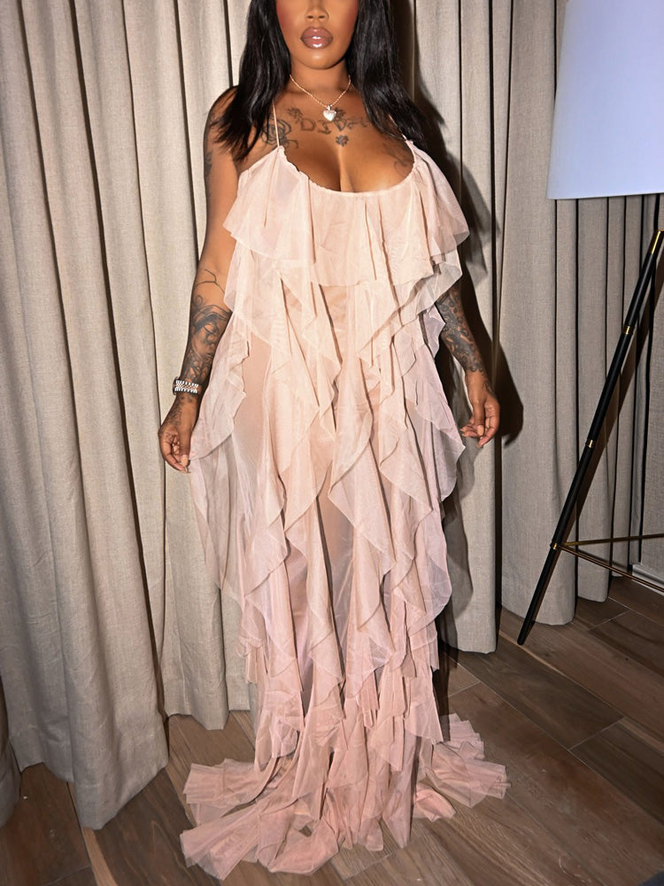 Woman wearing a long, light pink, ruffled chiffon dress with spaghetti straps.