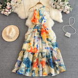 Full view of a sleeveless abstract floral print maxi dress with a tiered hem and a cinched waist, displayed on a hanger.