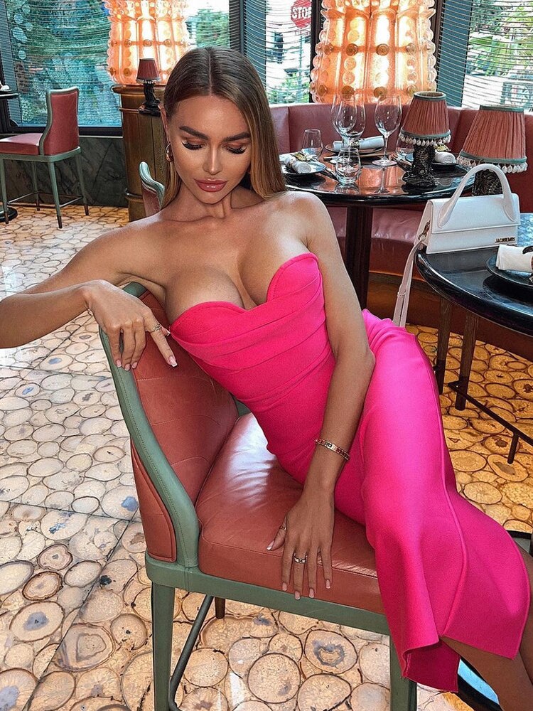 Woman in a bright pink strapless midi dress sitting in a chair in a restaurant
