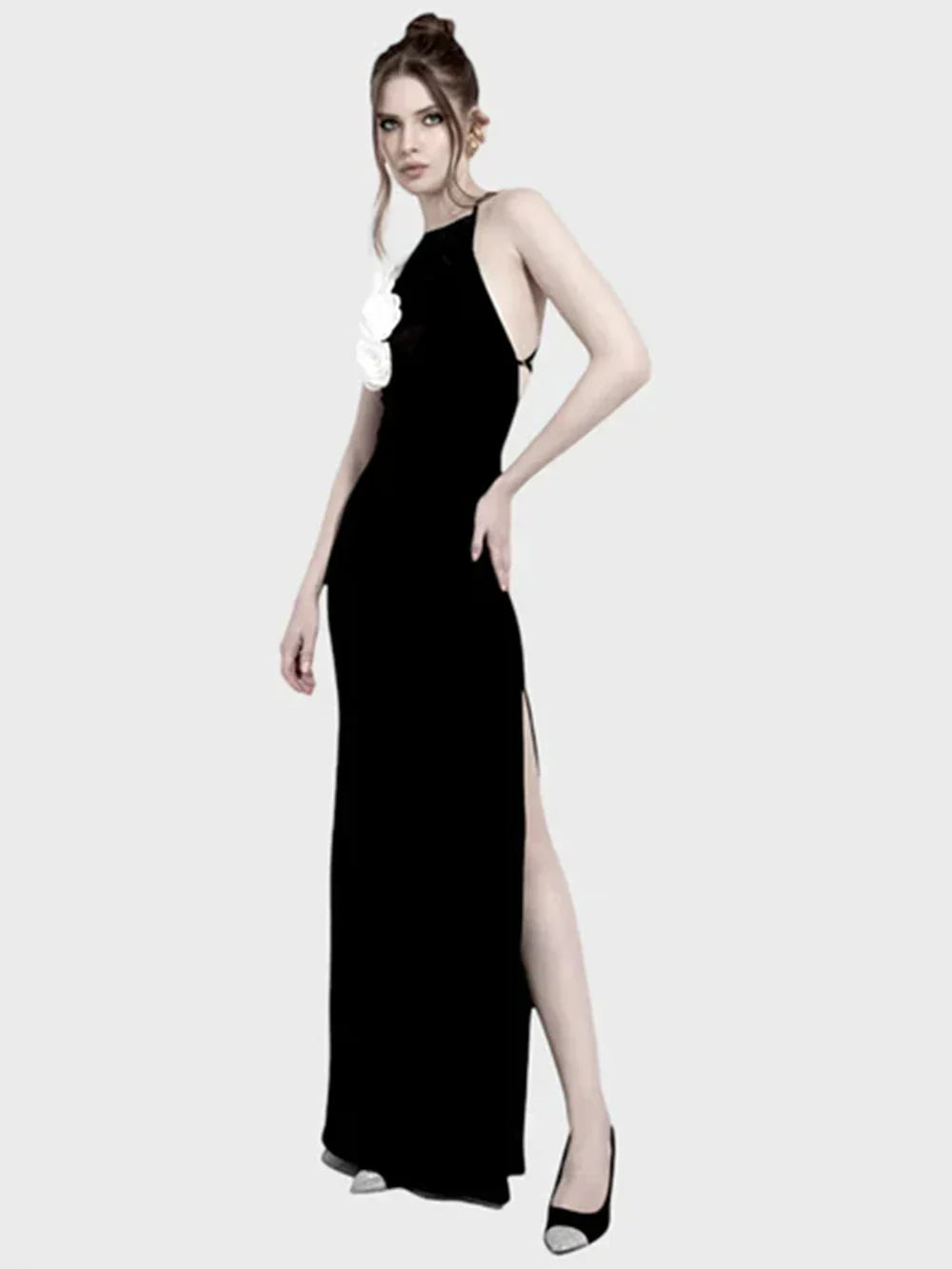 woman wearing a black floor-length halter dress with a high slit and white floral embellishments on the bodice