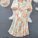 A full view of a floral print satin dress with bell sleeves and a tie closure.