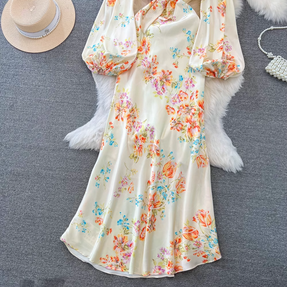 A full view of a floral print satin dress with bell sleeves and a tie closure.