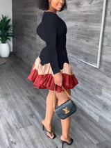 Side view of a woman in a black long-sleeved dress with a tiered, ruffled hem.