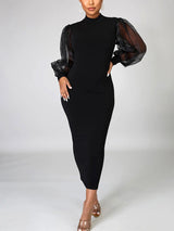 Close-up of the black dress highlighting the mock neckline and sheer sleeve details.