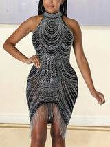 Close-up of a woman wearing a black sleeveless halter neck mini dress with elaborate rhinestone patterns