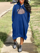 Woman wearing a royal blue hooded midi dress with a pumpkin graphic print and leopard pattern, standing outdoors.