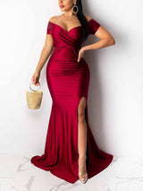 woman wearing a floor-length deep red satin gown with an off-the-shoulder neckline and a high slit