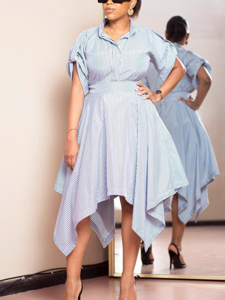 Front view of a woman in a blue and white striped shirt dress, standing with her hand on her hip.
