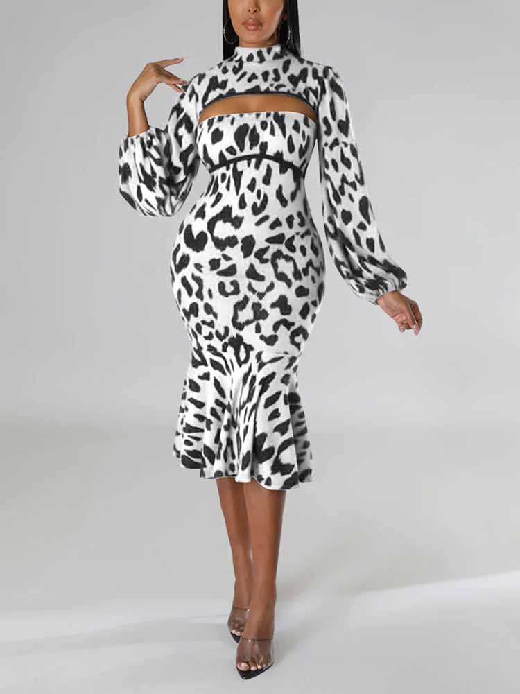 Woman wearing a black and white leopard print knit dress with a high neck, cut-out detail, long puff sleeves, and a mermaid hemline, posing with one hand on her hip.