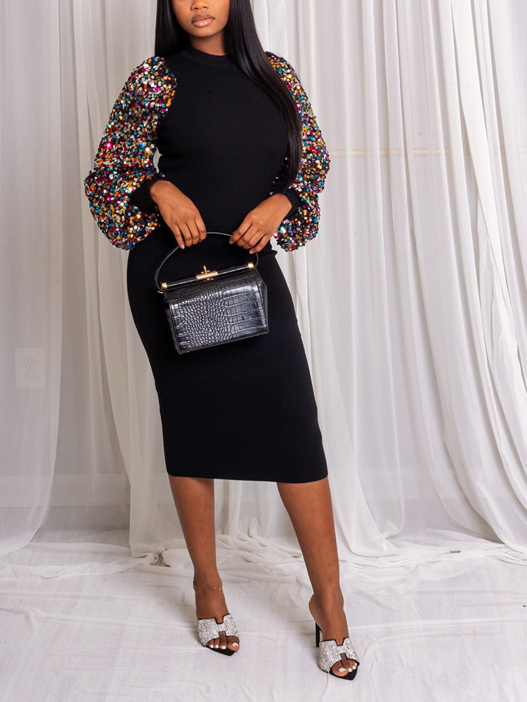 Woman wearing a black midi dress with sequined balloon sleeves, holding a black handbag.