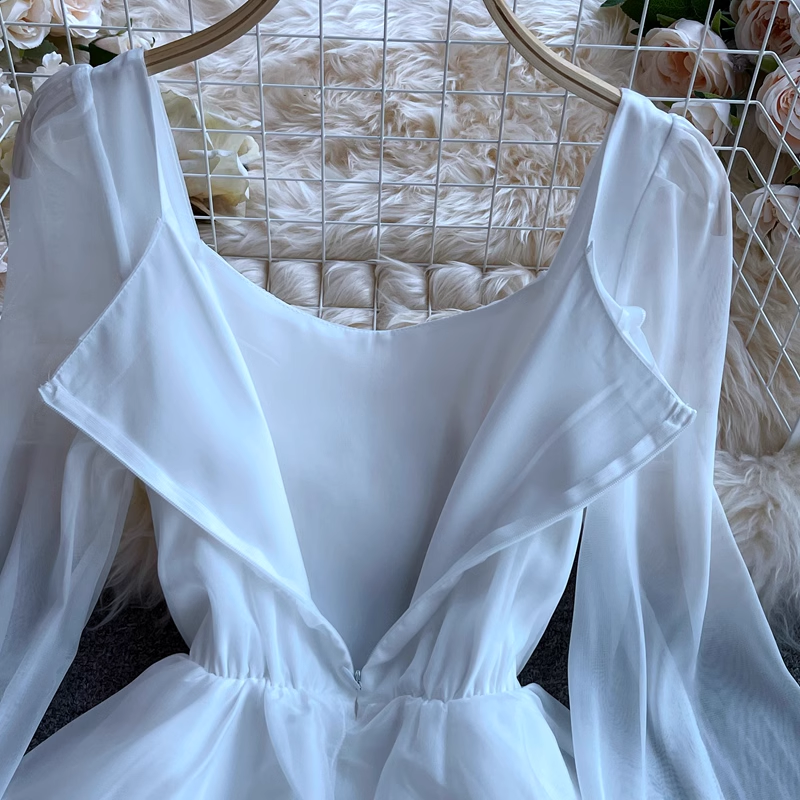 Back view of a white dress showing the scoop neckline and zipper closure