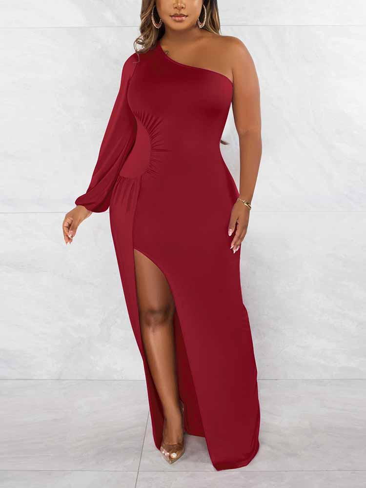Woman wearing a long, red, one-shoulder dress with a high slit and a long sleeve on one side.