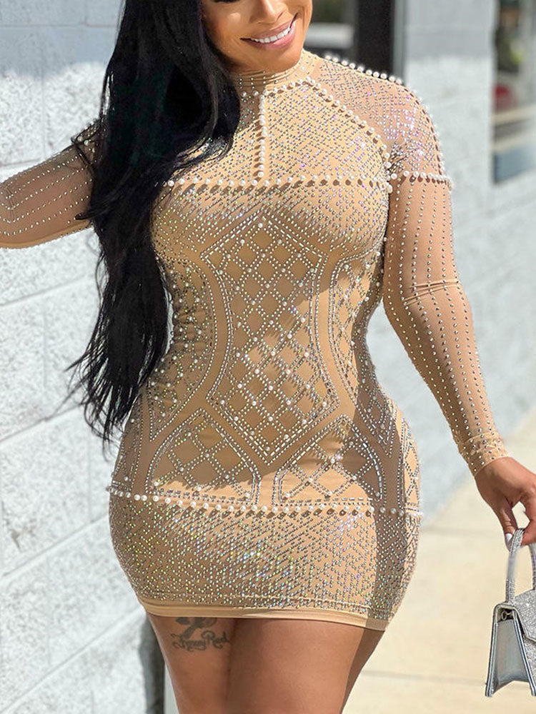 Close-up of a woman's torso showcasing the detailed rhinestone and pearl beading on a sheer mesh dress.