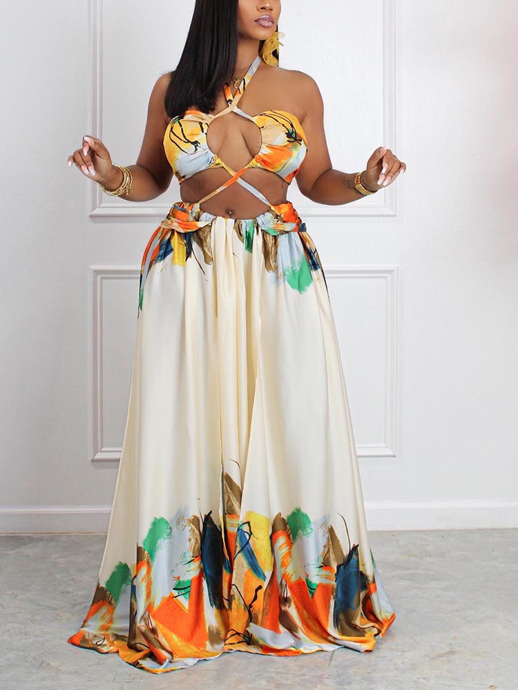 woman wearing a cream colored abstract print halter neck maxi dress with cut-out details and a side slit