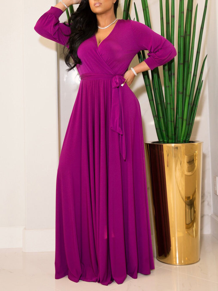 Woman wearing a rich magenta maxi dress with a wrap neckline and long sleeves.