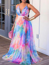 Woman wearing a colorful tie-dye maxi dress with a high slit and plunging neckline, holding a pink basket purse.