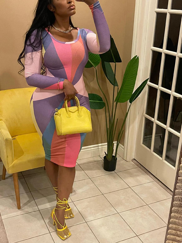 Full body shot of a woman in a long-sleeved, bodycon midi dress with a vibrant geometric pattern, accessorized with yellow shoes and a yellow purse.