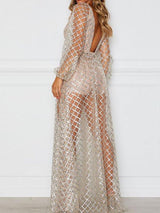 Rear view of a woman in a long, sheer, sparkling gold dress with long sleeves and a low back, indoors.